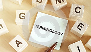 Wooden cubes with letters of the alphabet, a piece of paper with the text TERMINOLOGYÃÂ  in the middle on a wooden table photo